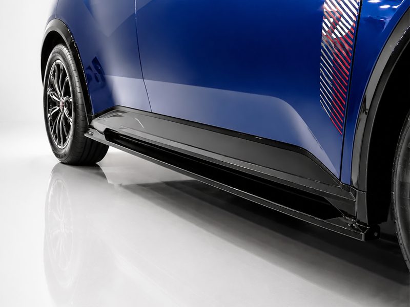 Close-up of a blue car's lower side panel with a black aerodynamic side skirt and visible wheel.