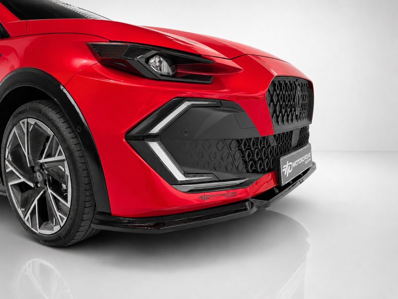 Close-up of a red car's front end, featuring a sharp headlight, honeycomb grille, and sculpted bumper.