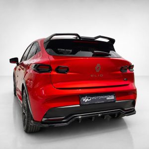 Rear view of a red Renault Clio hatchback with a black roof spoiler and roof rails in a studio setting.