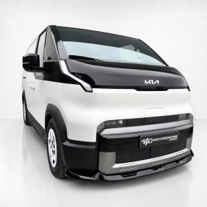 White and black futuristic van in a studio, front three-quarter view with bold lighting and MotorDrome Design plate visible