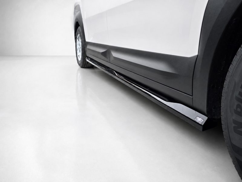 Side view of a white van with a chrome running board along the lower edge and a visible wheel.