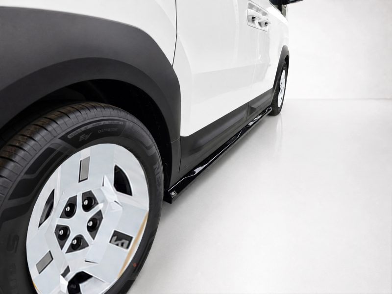 Close-up of a white SUV's front wheel and side running board in a bright studio, showing tire tread and black rocker panel.