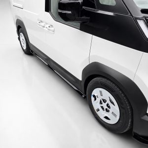 Close-up side view of a white and black van showing the wheel, door handles, and running board repair/trim details.