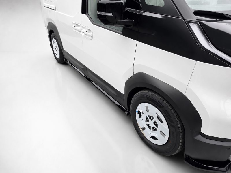Close-up side view of a white and black van showing the wheel, door handles, and running board repair/trim details.