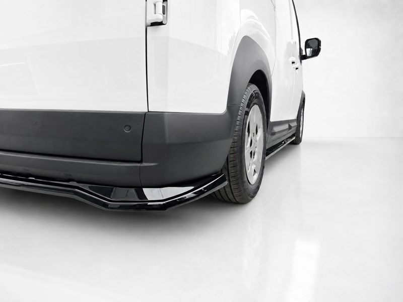 Rear side view of a white van, showing the black lower bumper, wheel, and side trim.