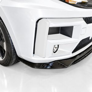 Close-up of a white car front with a large black front splitter, angular bumper details, and a wheel visible on the left