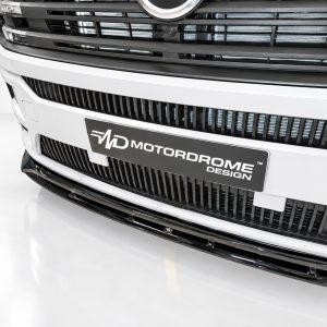 Front view of a white vehicle’s grille with a black 'Motordome Design' plate.
