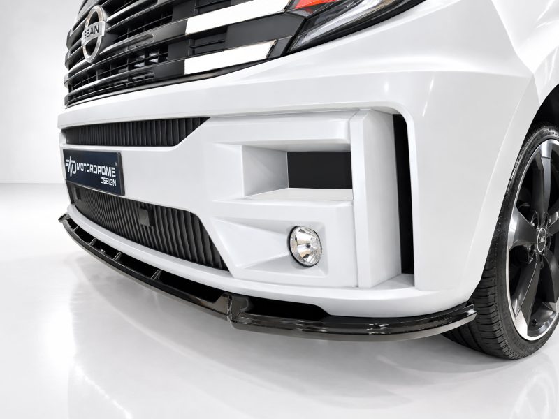 White car front close-up showing an aggressive bumper design, black grille, fog light, and a MotorDome Design plate
