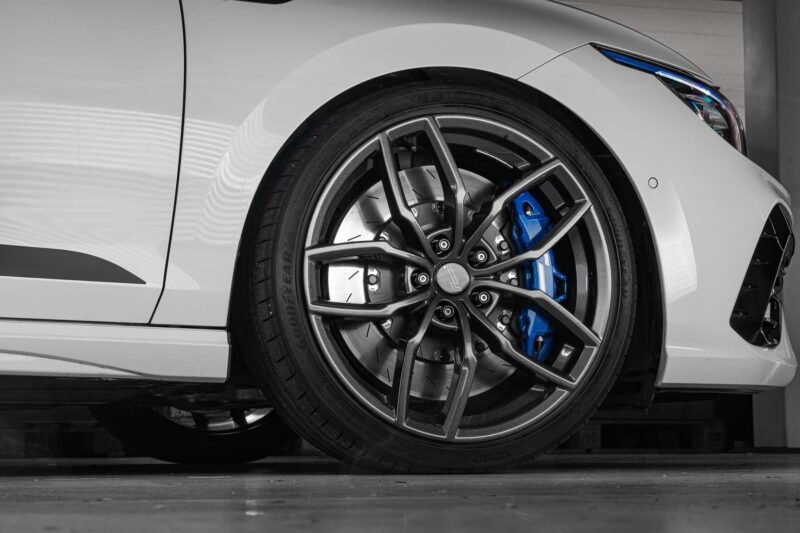Mk8-R-Lowering-Springs-1jpg - OPSHOLDERS Close-up of a white car's front wheel showing a silver alloy rim and blue brake caliper behind it.