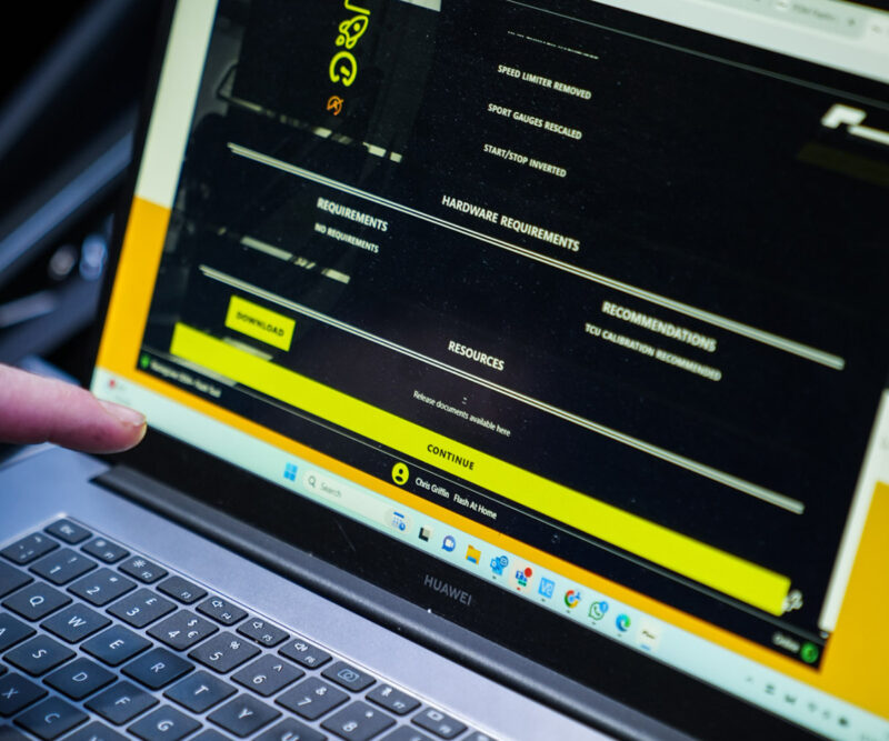 Racingline-PDM-Home-Tuning-VWR031000_4-1jpg - OPSHOLDERS Close-up of a laptop screen showing a dark software interface with yellow highlights and a finger pointing at a Download button.