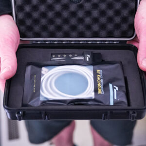 Racingline-PDM-Home-Tuning-VWR031000_6-1jpg - OPSHOLDERS Person holds an open protective case revealing a packaged racing accessory with a white circular coil and the 'RACINGLINE' branding visible inside.