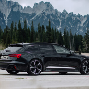 Racingline-VWR436001-fitted-1jpg - OPSHOLDERS Black luxury station wagon driving on a paved road with rugged mountains and pine trees in the background