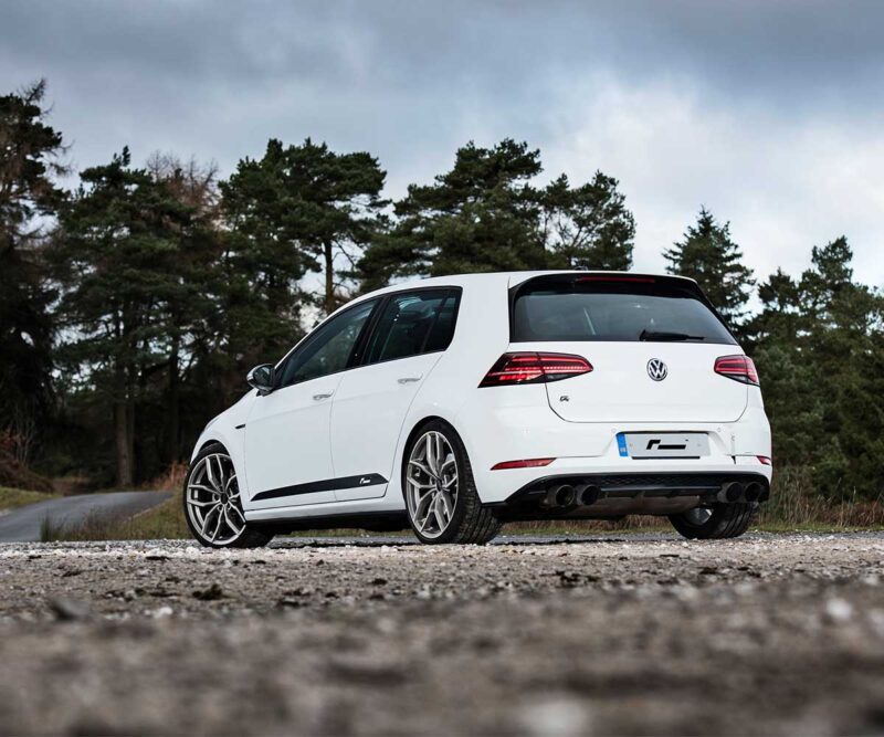 Racingline_Lowering_Springs_MK7Rjpg - OPSHOLDERS Rear three-quarter view of a white Volkswagen Golf R parked on a rocky dirt road with a forest backdrop.