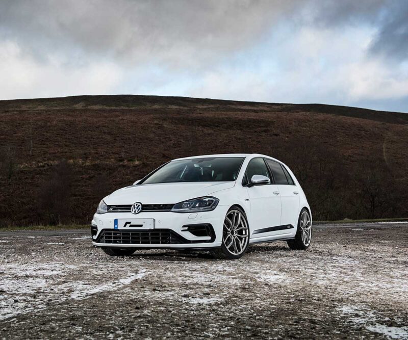 Racingline_Lowering_Springs_MK7R_1jpg - OPSHOLDERS White Volkswagen Golf R parked on a gravel lot with a barren hillside and cloudy sky in the background
