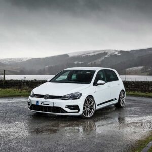 Racingline_Lowering_Springs_MK7R_2jpg - OPSHOLDERS White Volkswagen hatchback parked on a wet asphalt road with a misty, hilly landscape in the background under a cloudy sky.