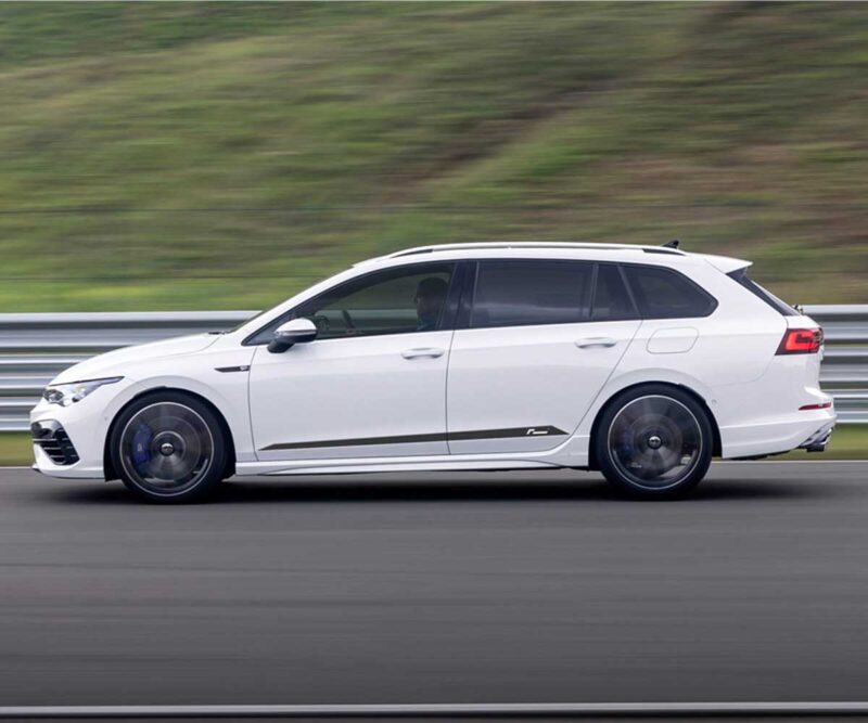 Racingline_Springs_MK8R-Estatejpg - OPSHOLDERS White station wagon in motion on a highway, blurred green landscape in the background, showcasing a side profile with dark windows and blue brake calipers visible through the wheels.