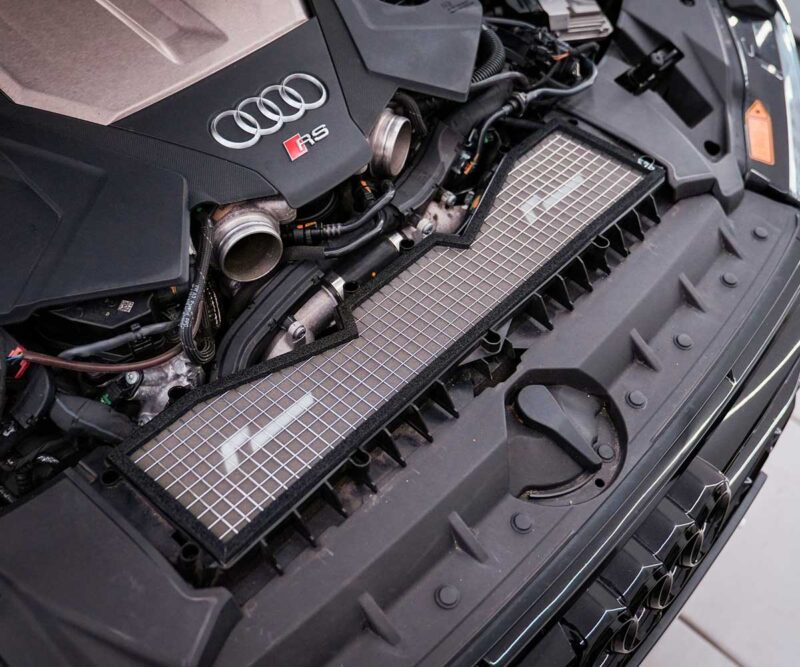 Close-up of an Audi RS engine bay with exposed components and a front grille mesh panel