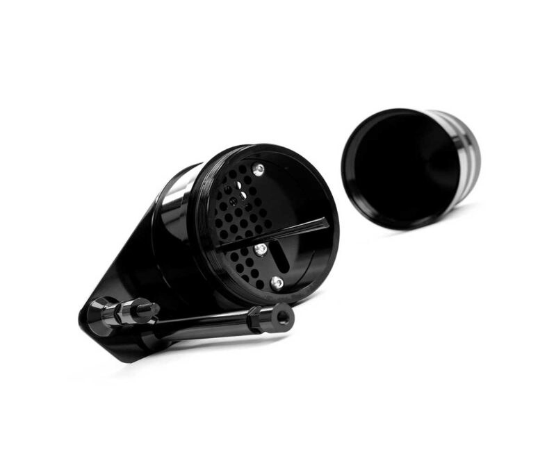 Black metal herb grinder opened to reveal grinding teeth and storage chamber, lid set to the side.