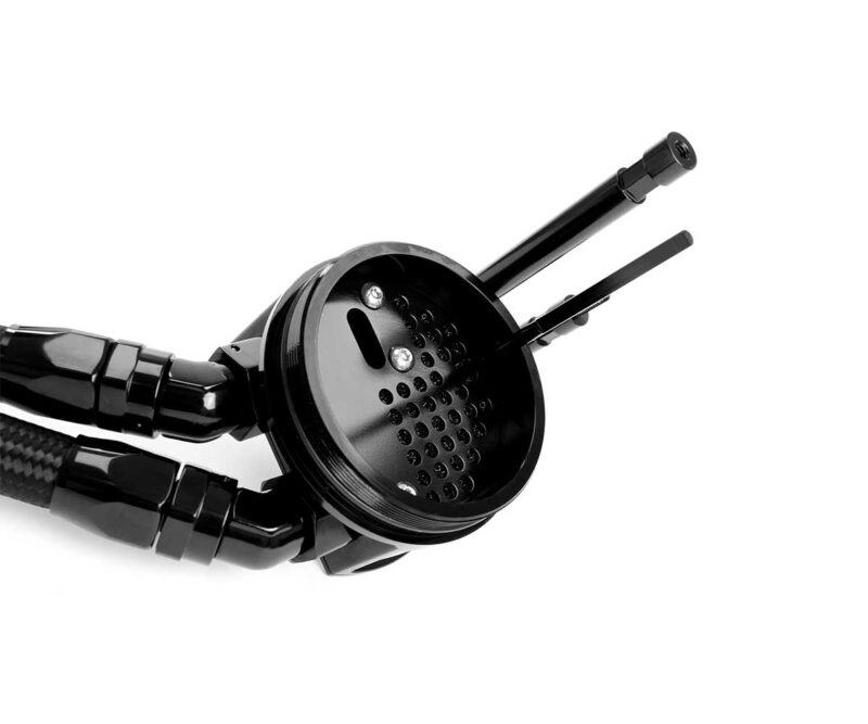 Close-up of a black circular metal component with many small holes, connected to a glossy arm or handle (industrial-looking). It resembles a perforated filter plate.