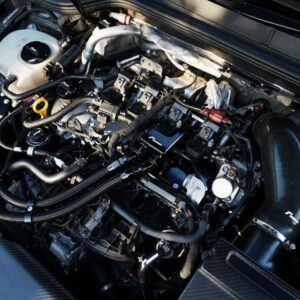 Close-up of a car engine bay showing hoses, cables, and fluid reservoirs with metal engine components visible