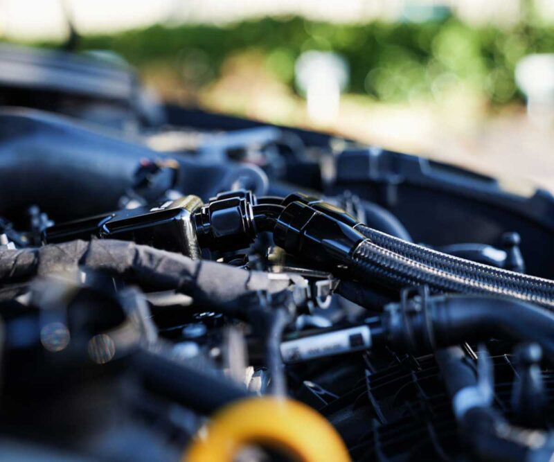 Close-up of a car engine bay focusing on hoses, clamps, and connectors.