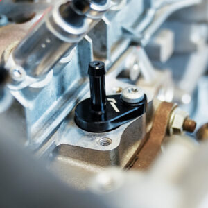 VWR140014_10-1jpg - OPSHOLDERS Close-up of a metal engine component with a black adjustment lever and bolts.