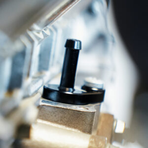 VWR140014_11-1jpg - OPSHOLDERS Close-up of a black vertical knob on an industrial machine with blurred metal surroundings