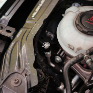 Close-up of a car engine bay showing the coolant reservoir cap labeled 160 kPa/23 psi and surrounding hoses and components.