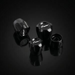 Set of four black glossy control knobs with white alignment marks arranged on a reflective black surface.