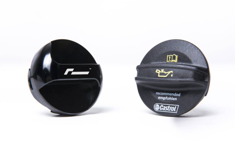 Two black round caps on a white surface, left cap plain and glossy, right cap branded with Castrol and the word 'recommended'.