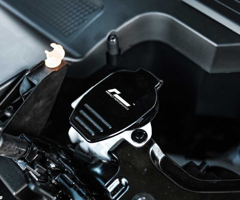 Close-up of a motorcycle handlebar featuring a black glossy throttle/adjustment plate labeled 'Perfect Performance' mounted near the grip.