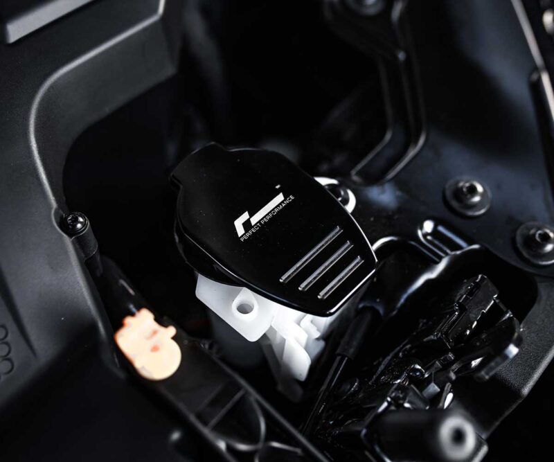Close-up of a black racing-style car pedal with a cap labeled 'F Perfect Performance' in a dark interior.