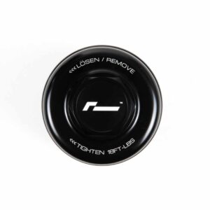 Black circular dial with a white center logo and edge text reading “LÖSEN / REMOVE” and “TIGHTEN 18FT-LBS” on a white background.