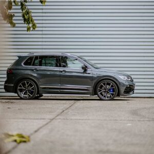 Side view of a dark-gray SUV parked on a concrete surface against a corrugated metal wall, chrome trim visible.