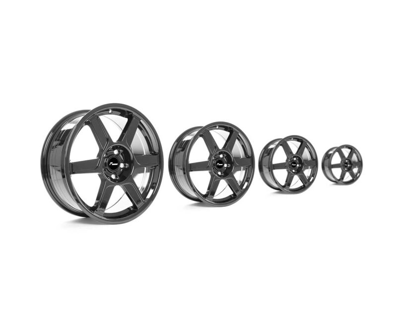 Set of shiny alloy car wheels in varying sizes arranged from largest to smallest.