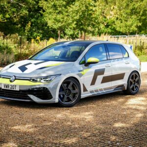 VWR610401_12jpg - OPSHOLDERS White Volkswagen hatchback with bold racing livery parked on a gravel driveway among trees, front view with lime accents and large decals on sides.