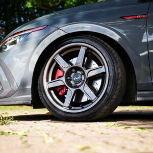 VWR610401_13jpg - OPSHOLDERS Close-up of a gray car wheel with a five-spoke alloy rim and red brake caliper visible behind it