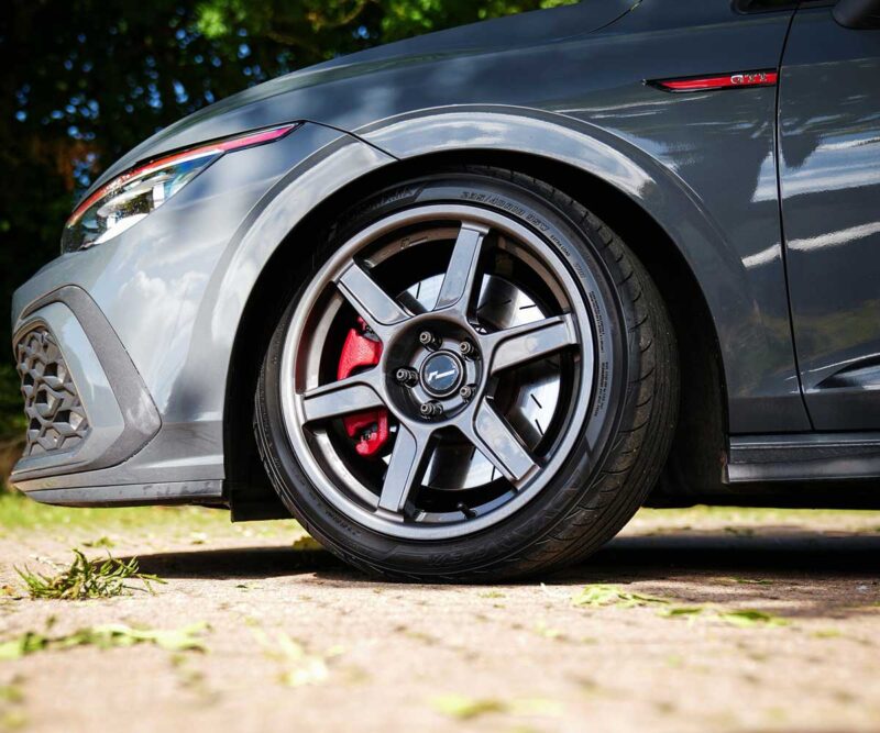 VWR610401_13jpg - OPSHOLDERS Close-up of a gray car wheel with a five-spoke alloy rim and red brake caliper visible behind it