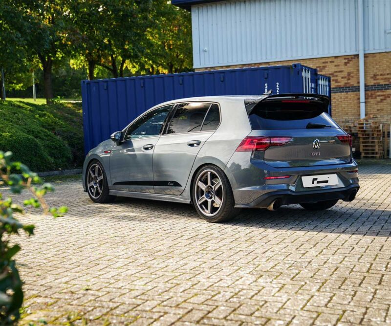 VWR610401_15jpg - OPSHOLDERS SilverVolkswagen Golf GTI hatchback parked in a lot with a blue shipping container and brick building in the background (rear three-quarter view).