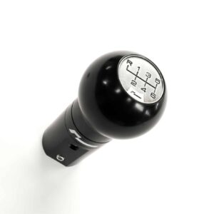 Close-up of a black manual gear shifter with a silver shift pattern showing 1–6 and R