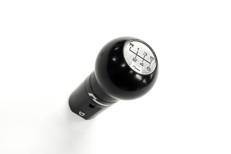 Close-up of a black manual gear shifter with a silver shift pattern showing 1–6 and R