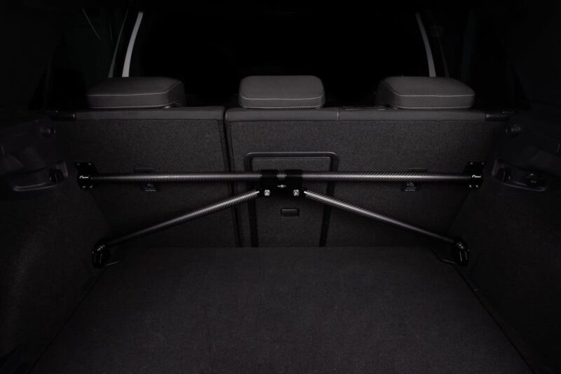 VWR81G700_3-1jpg - OPSHOLDERS Carbon-fiber crossbar bike rack installed across the rear cargo area behind the back seats of a vehicle, securing items in the trunk.