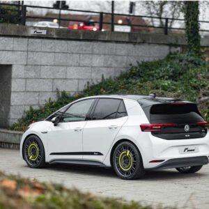 VW_ID3_Springsjpg - OPSHOLDERS White Volkswagen ID.3 hatchback with black rear section and neon-yellow wheel rims parked by a stone wall.