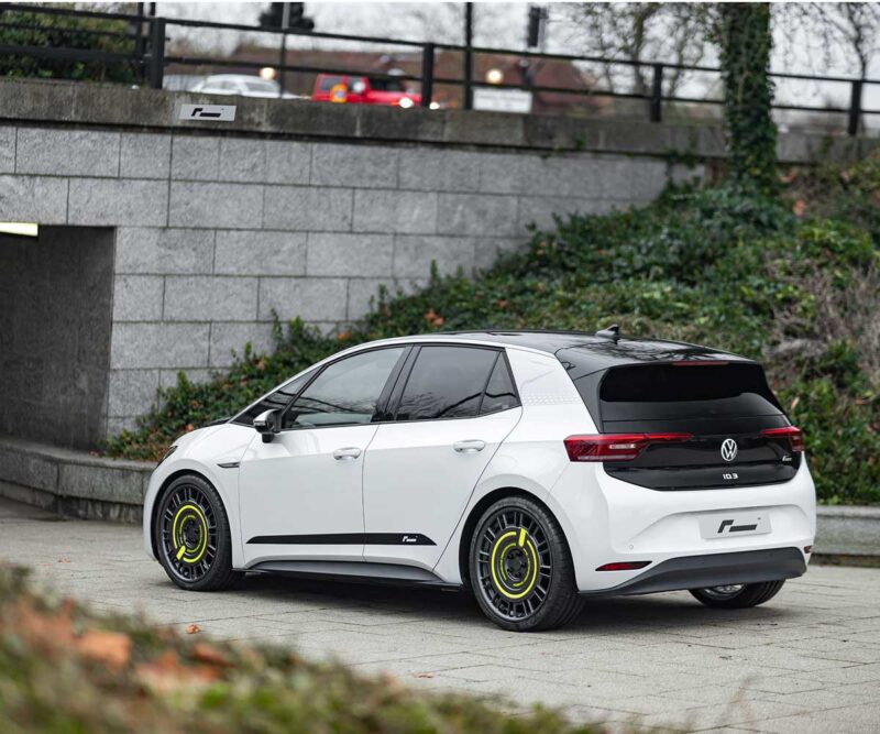 VW_ID3_Springsjpg - OPSHOLDERS White Volkswagen ID.3 hatchback with black rear section and neon-yellow wheel rims parked by a stone wall.