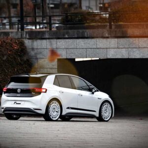 VW_ID3_Springs_1-1jpg - OPSHOLDERS White Volkswagen electric hatchback (ID.3) viewed from rear-three-quarters parked on a paved area near a tunnel in an urban setting, autumn leaves nearby.