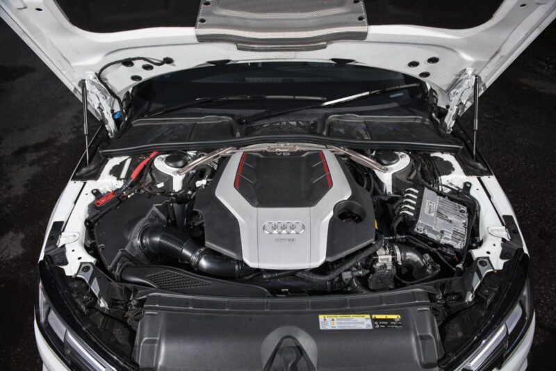 audi-b9-a4s4-strut-brace_28703771618_o-1jpg - OPSHOLDERS Open hood reveals a modern Audi V6 engine with silver and red accents in a clean engine bay, front view in white car.