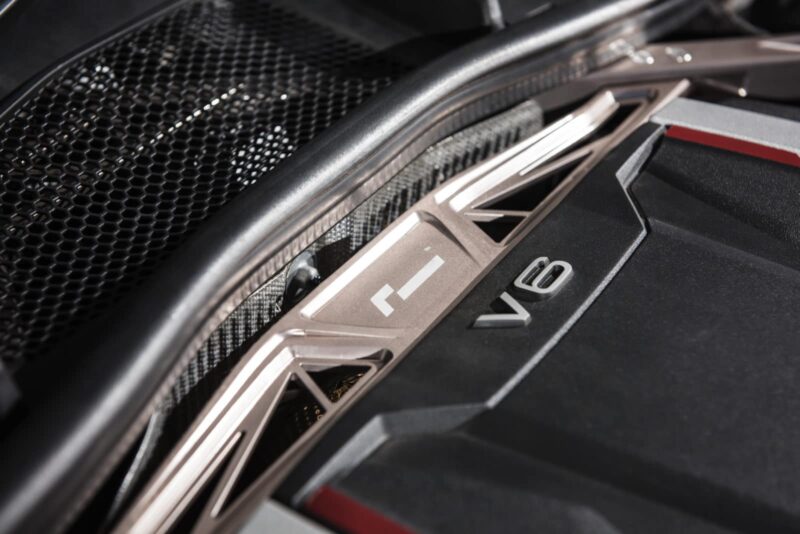 audi-b9-a4s4-strut-brace_28703794348_o-1jpg - OPSHOLDERS Close-up of a car engine bay with a prominent V8 badge and metallic trim near a vented grille.