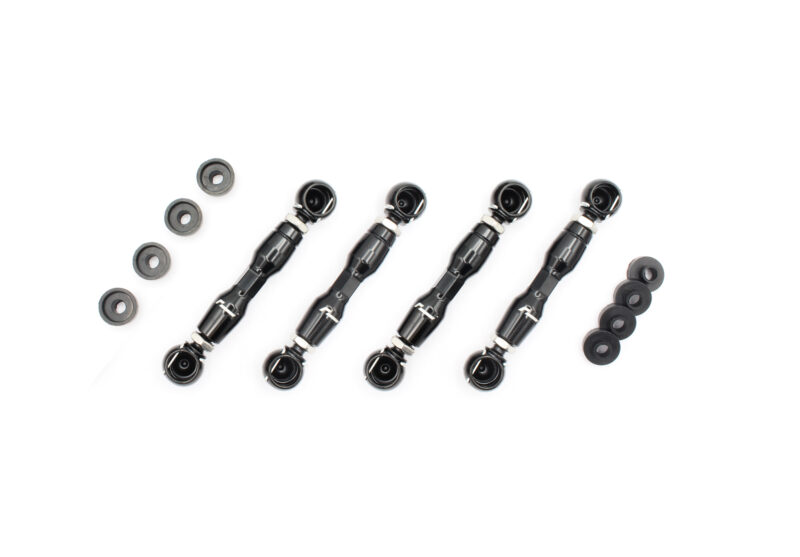 Four black robotic arms with circular tips laid diagonally on a white surface, with scattered round washers nearby.