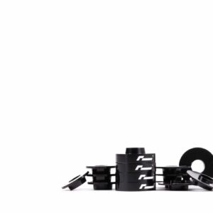dead-set-4_45145483134_o-scaled-2jpg - OPSHOLDERS Close-up of black interlocking bricks with white logos arranged in a circular stack on a white background.
