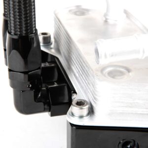 Macro close-up of a braided hose connected to a black mounting bracket beside a silver machined metal block with bolts.